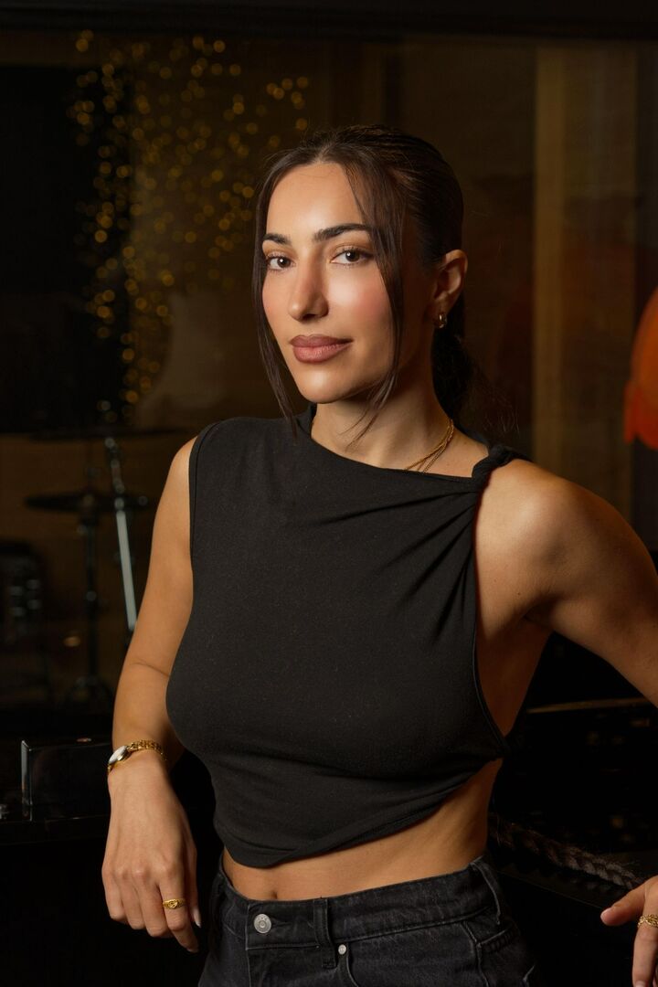 NOURI stands facing the camera wearing a black singlet top