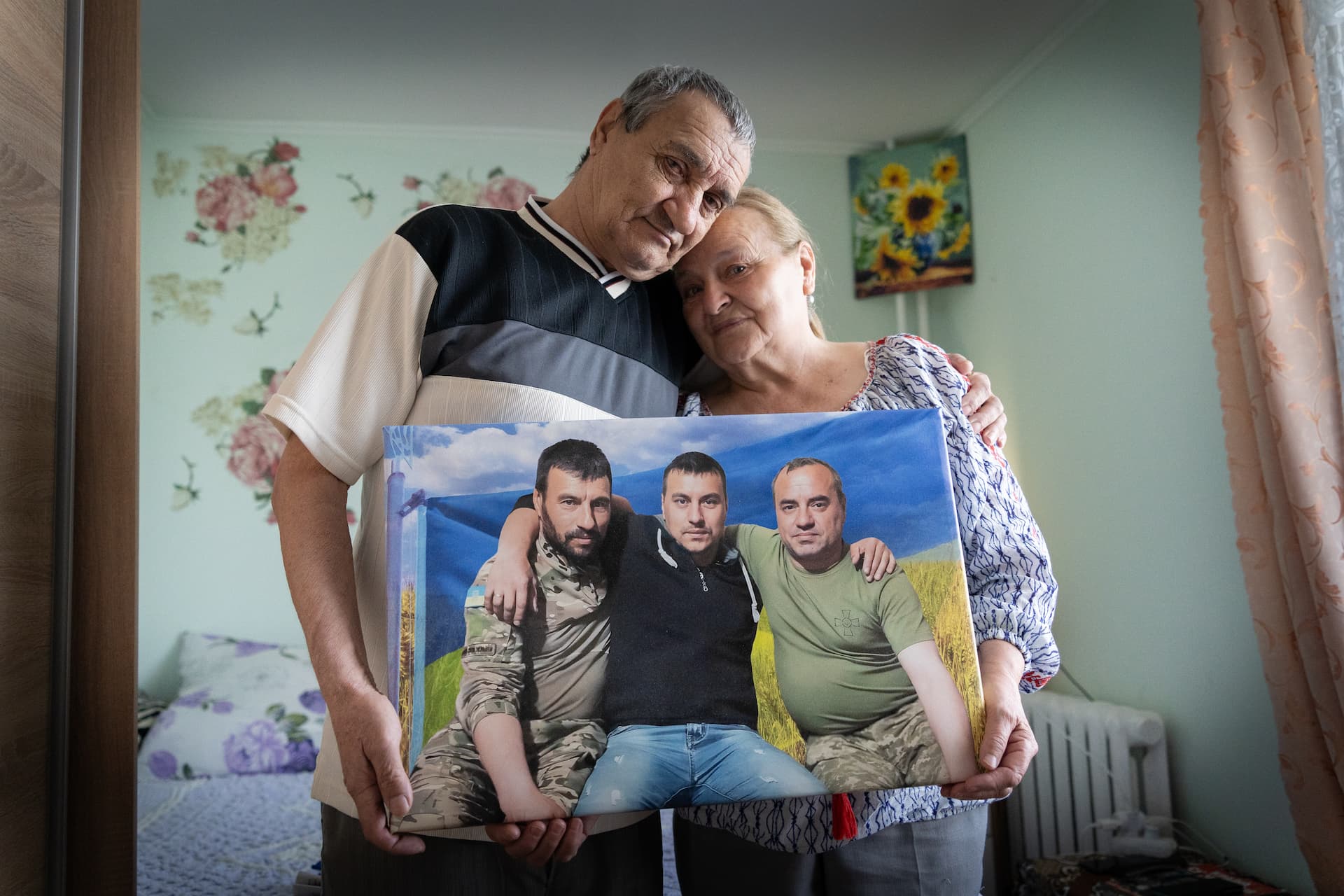 Mariia and Anatolii, who were displaced by the war in Ukraine, hold a picture of their three sons
