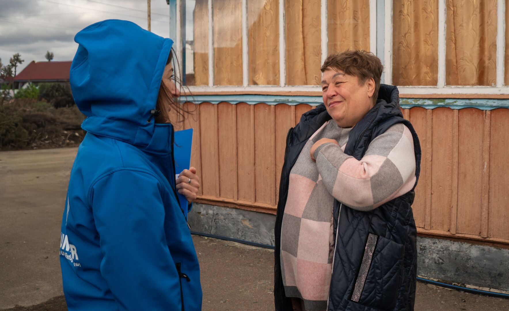 A UNHCR staff member speaks with Larysa outside her home in central Ukraine, where UNHCR supported repairs to improve living conditions for displaced families.