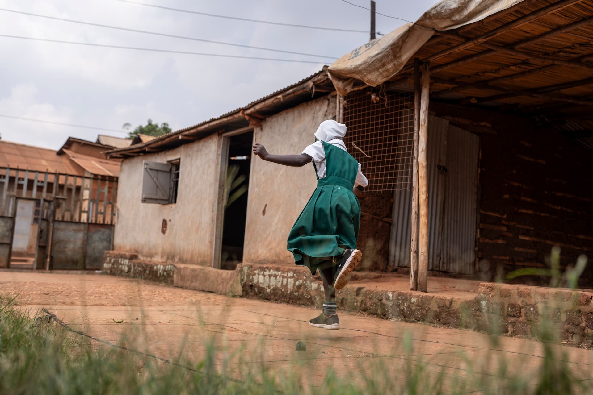 Sudanese refugee Leila plays hopscotch in the yard outside her home in Kampala, Uganda