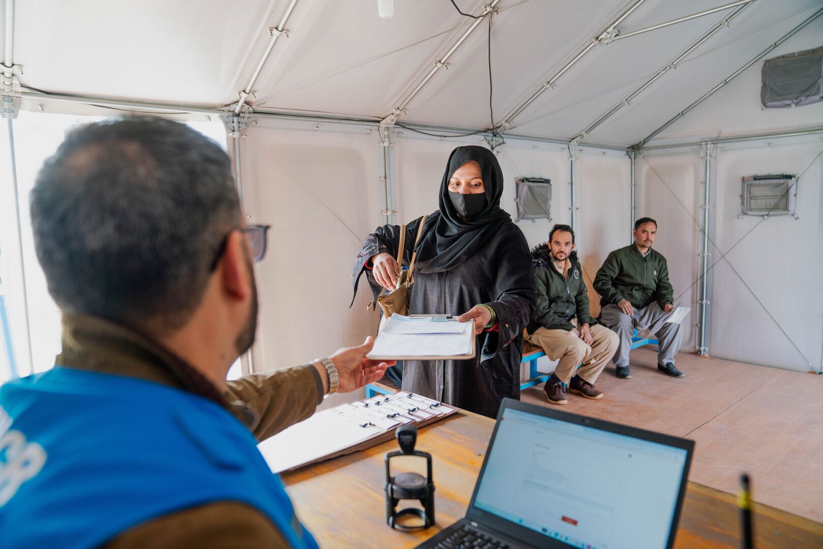 A woman wearing a burka receives assistance from a UNHCR staff member in Afghanistan