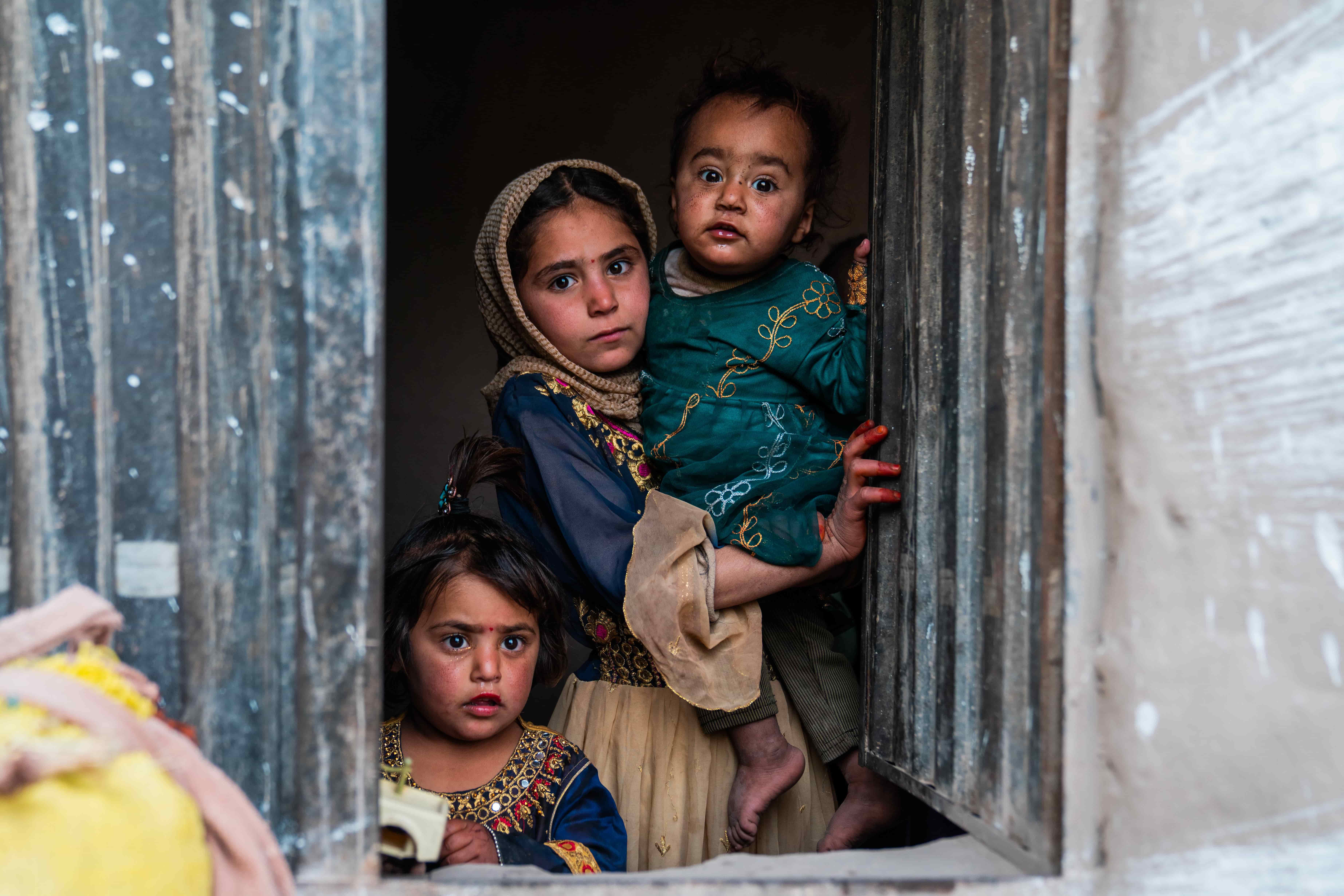 Children look out from the doorway of a new sustainable home, built with UNHCR support, in Nangarhar province, Afghanistan.